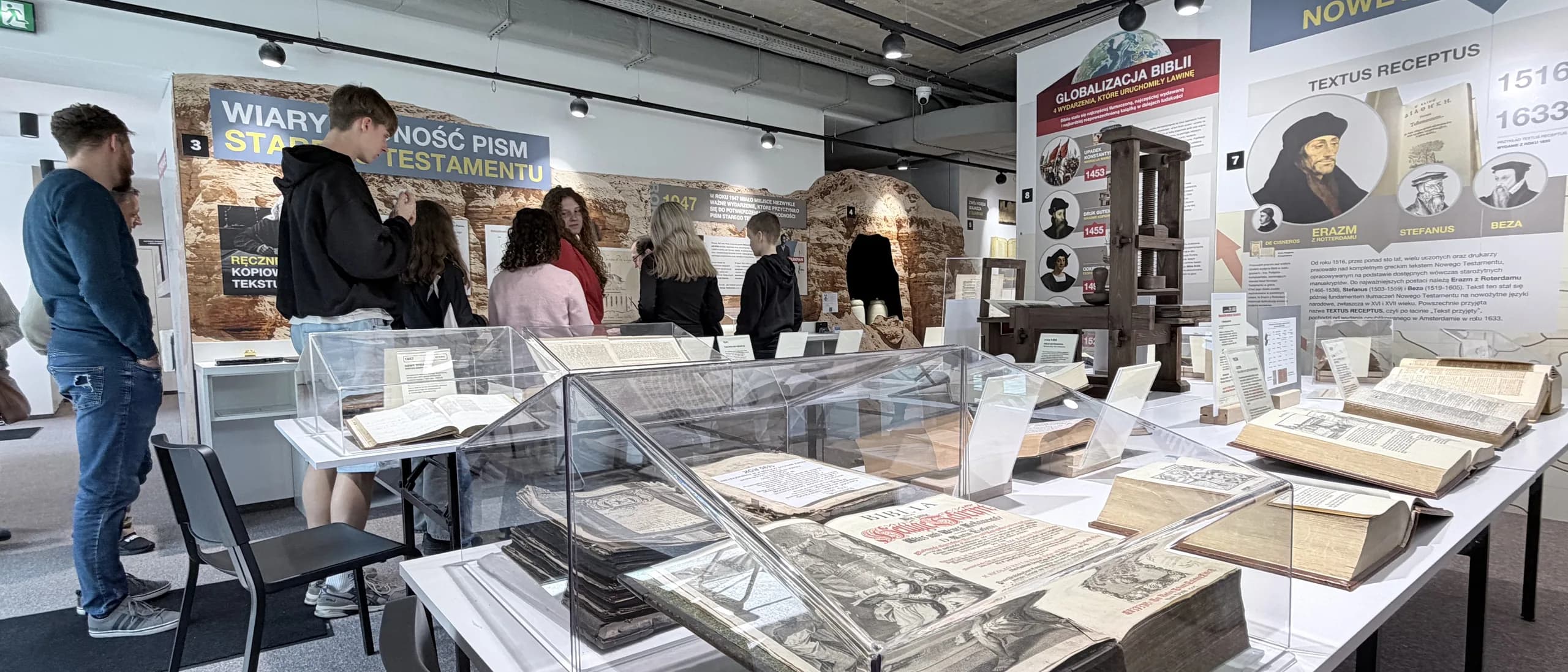 Zwiedzający przy gablotach z księgami w sali wystawowej Muzeum Biblii w Ustroniu.
